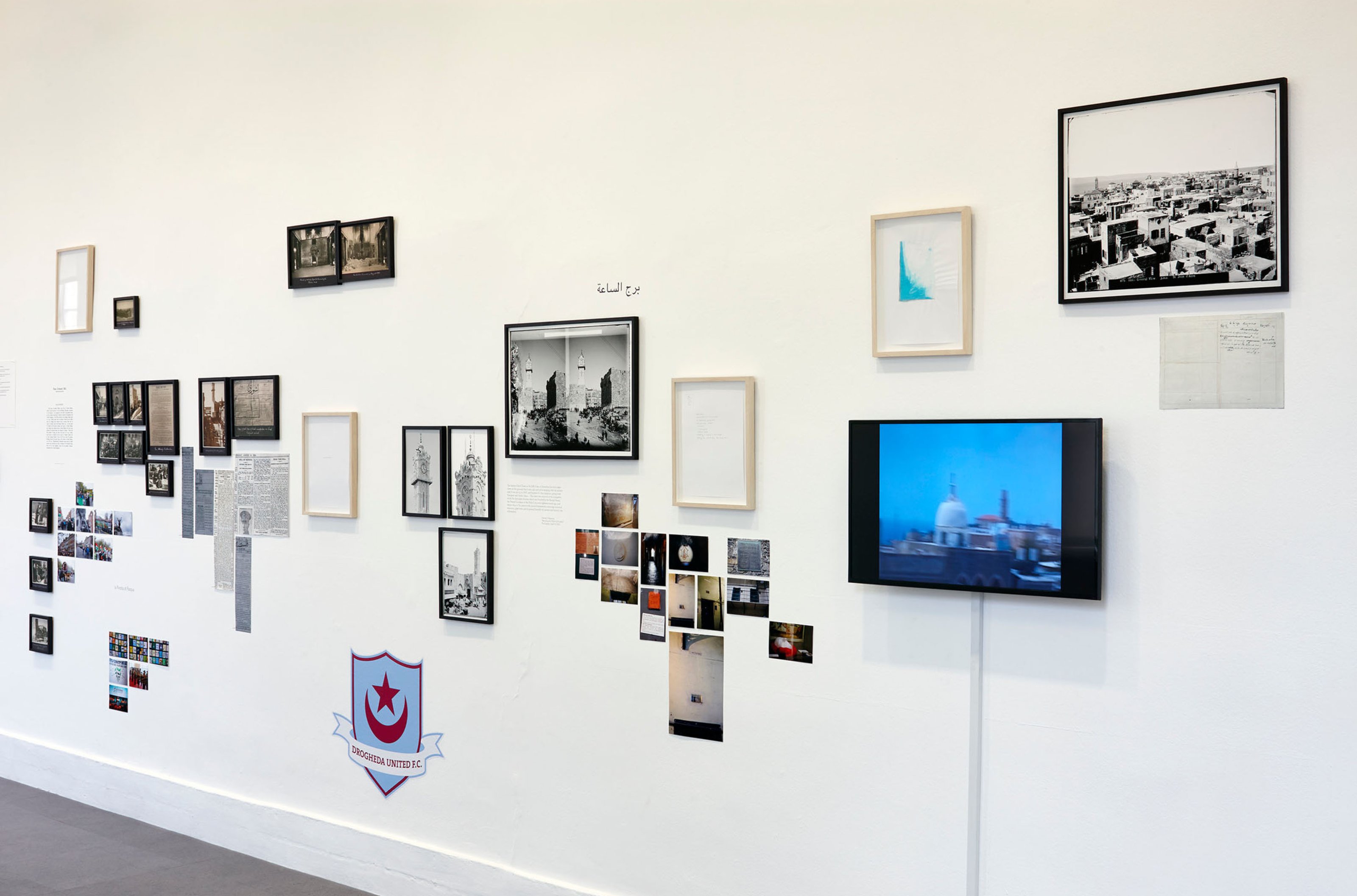 Multiple artworks are hanging on a white-wall of an art gallery.