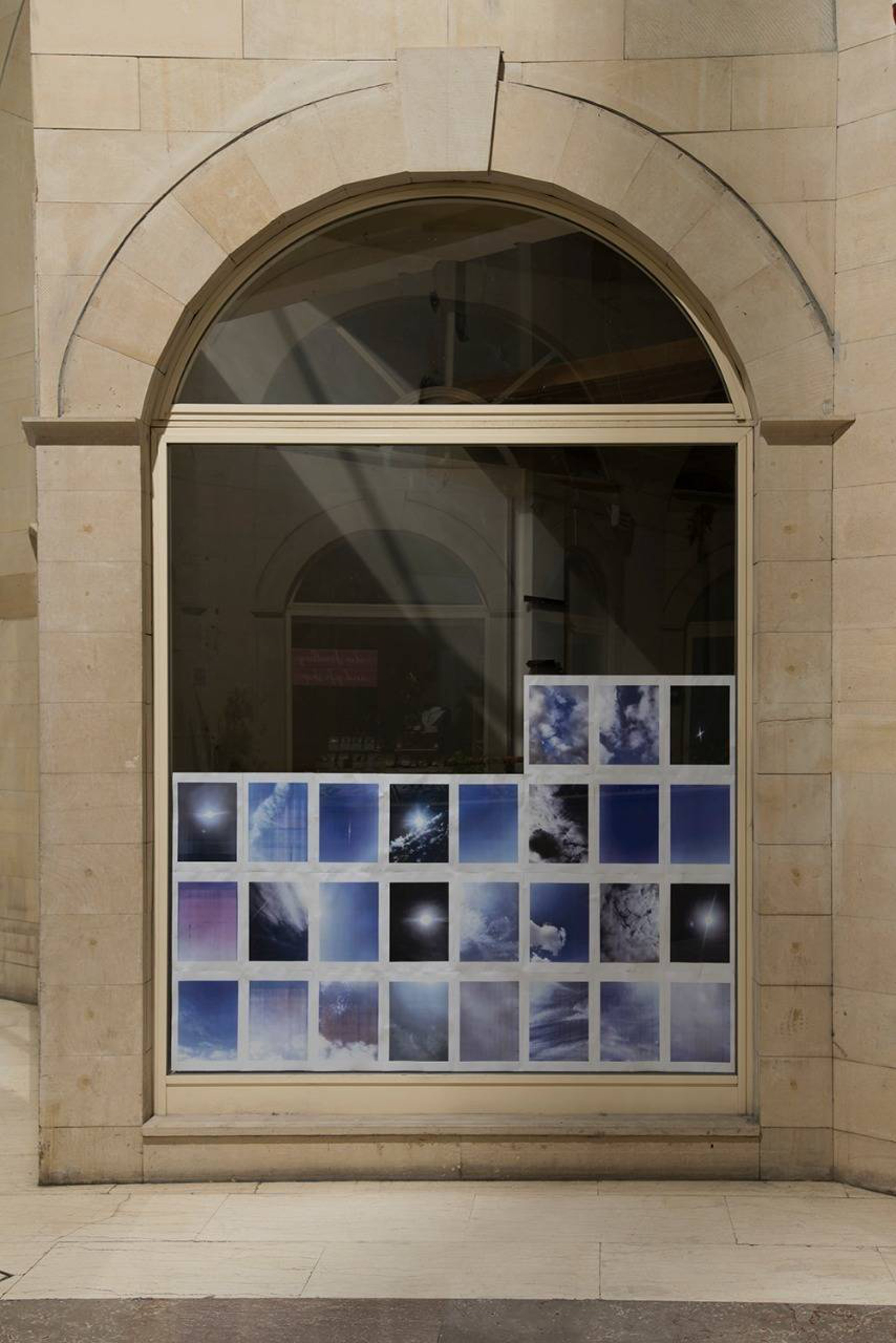 27 pieces of photographs are hung on the large window seen from the outside.