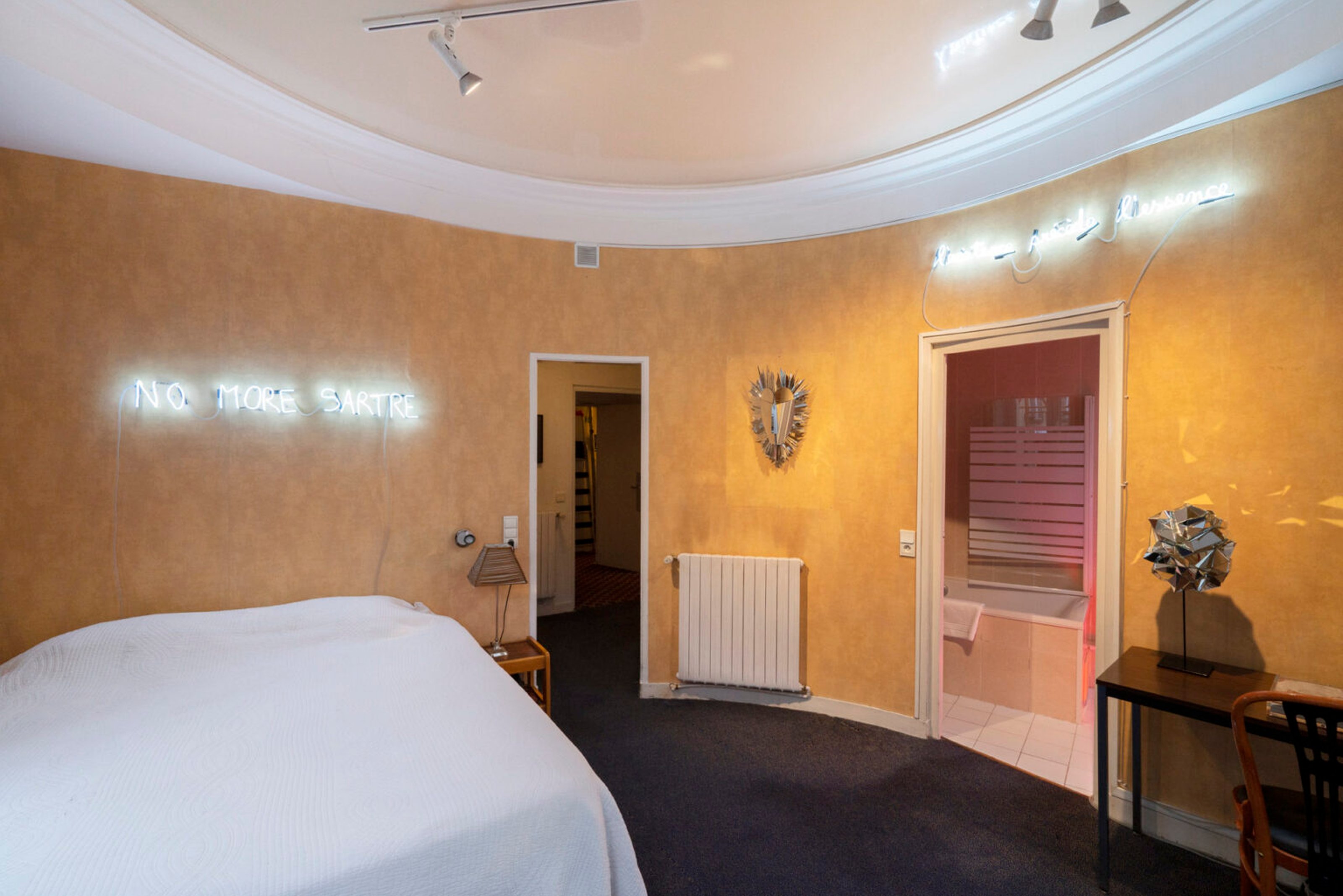 A double bed with a white cover in a circular room with yellow walls.