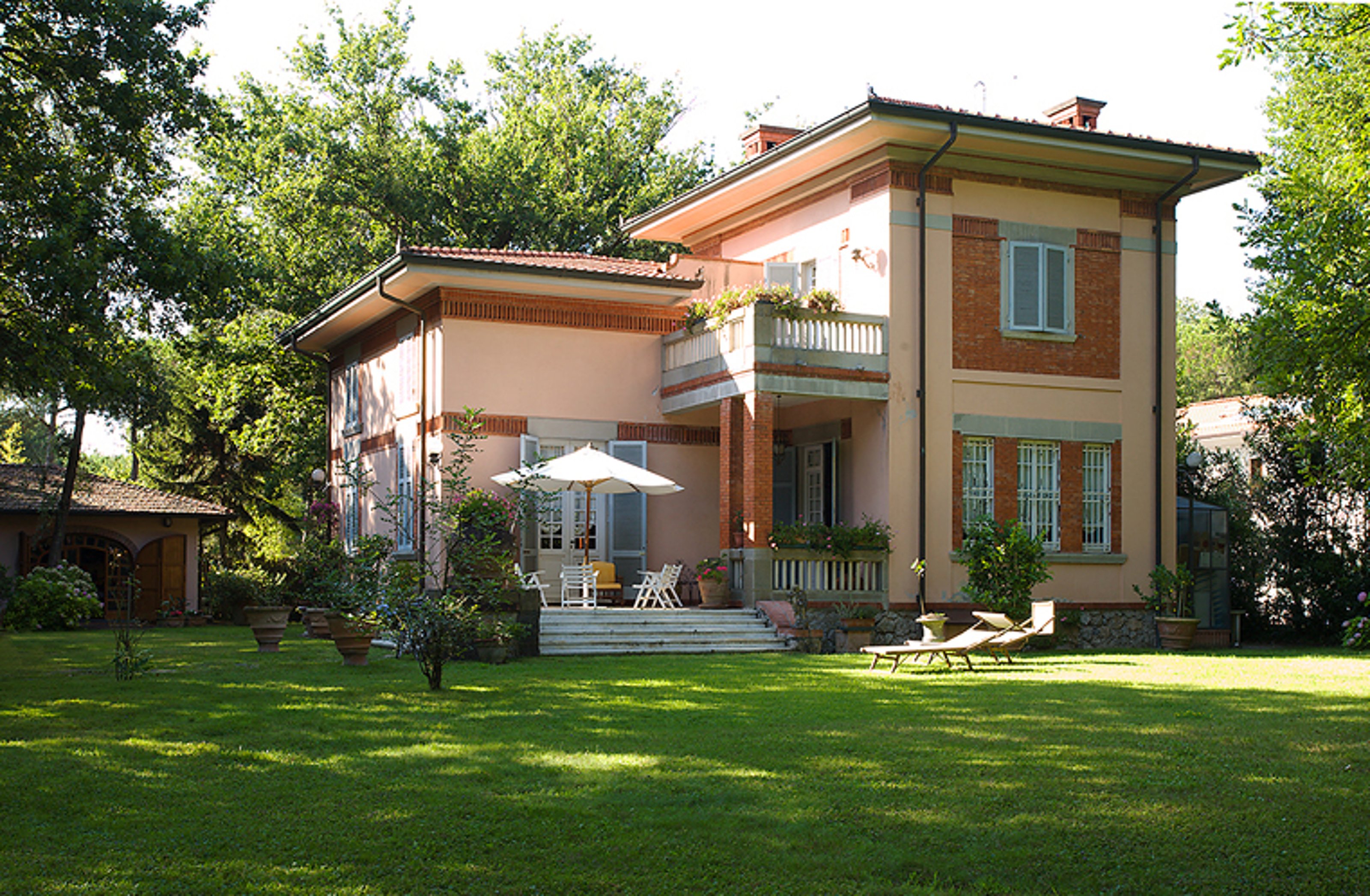 A two-storey villa with a cream-colored green grassy garden.