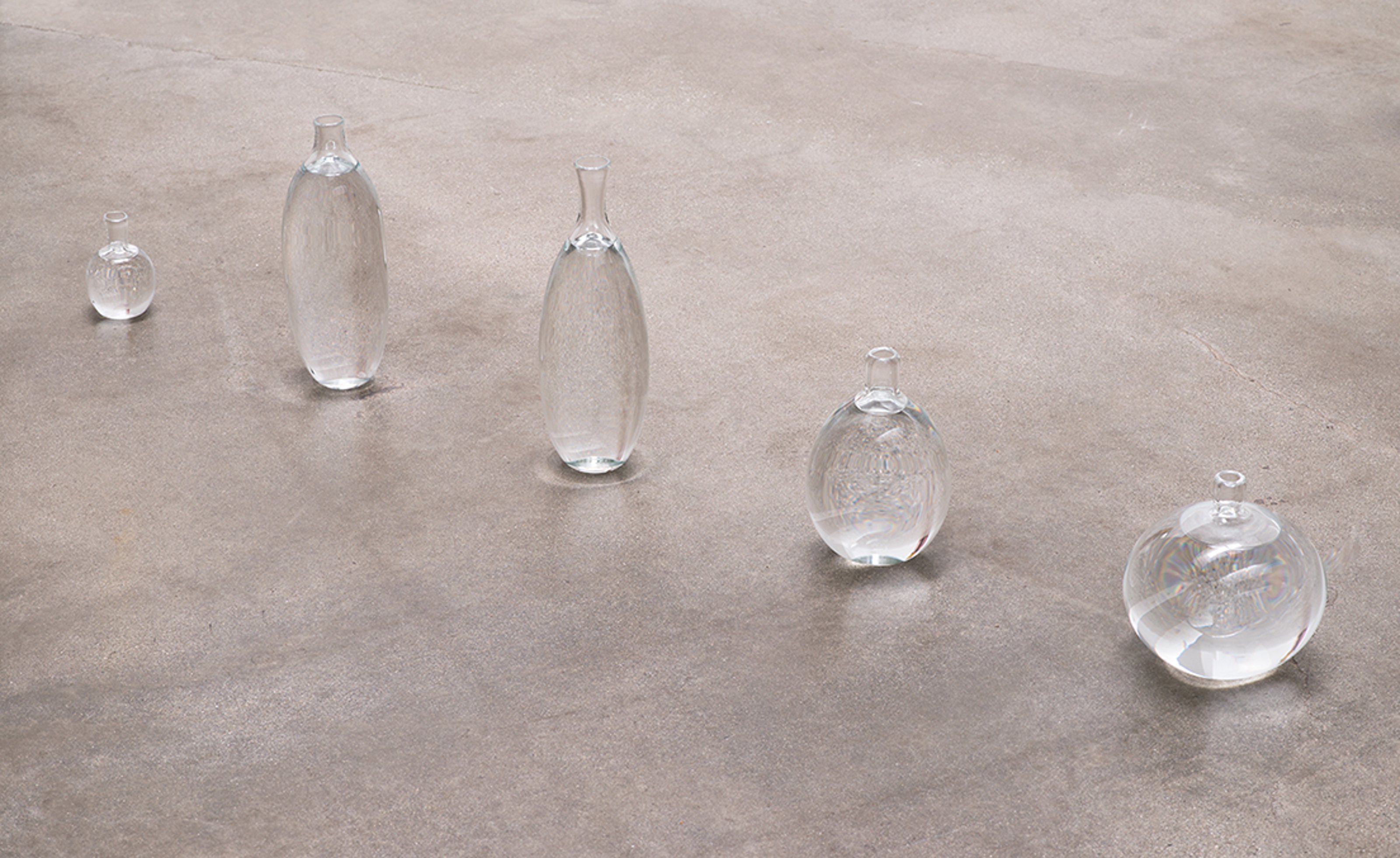 Botellas de vidrio llenas de agua de varios tamaños instaladas en una línea en el suelo