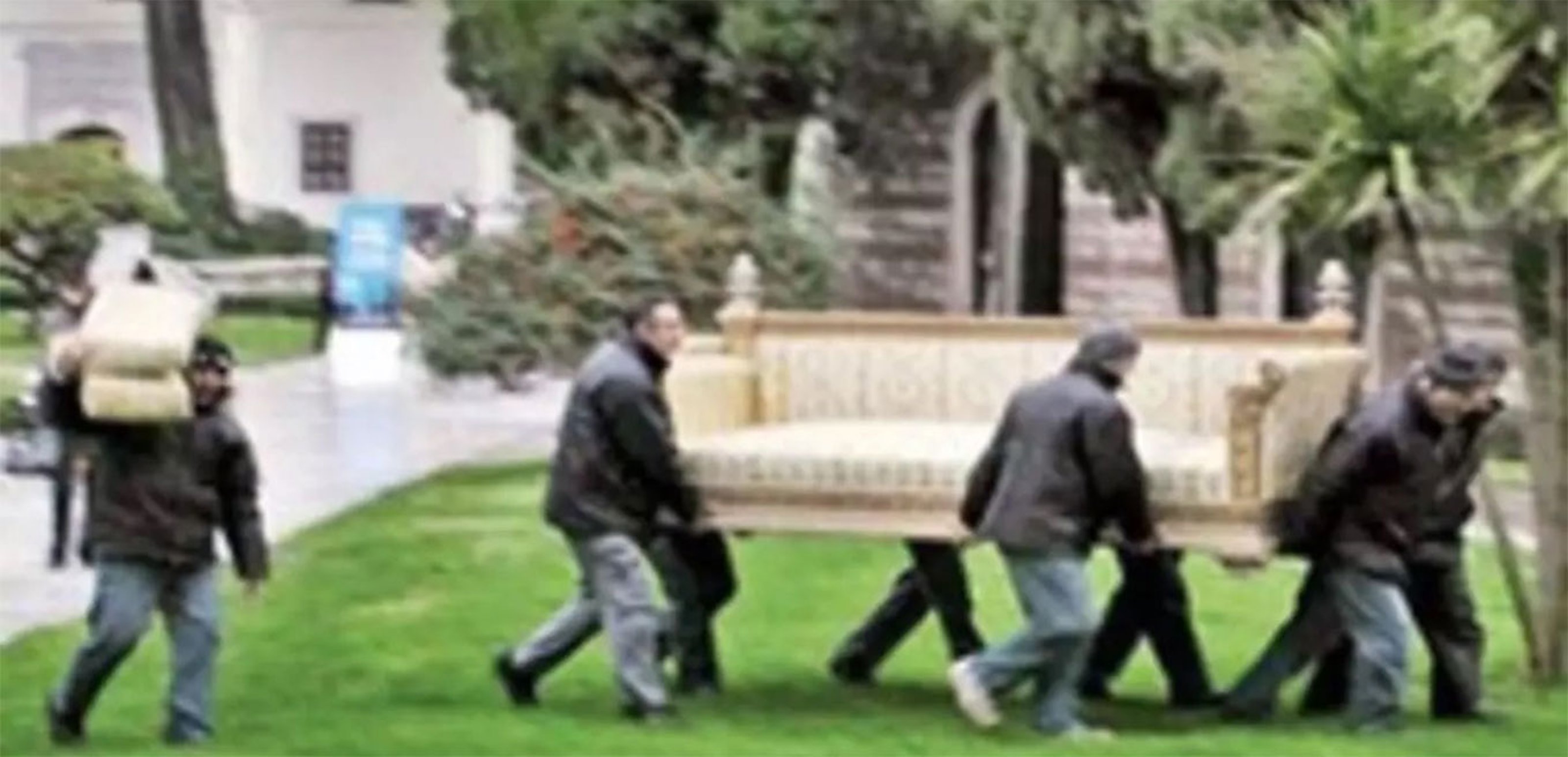 A group of men walk with a throne in their hands.