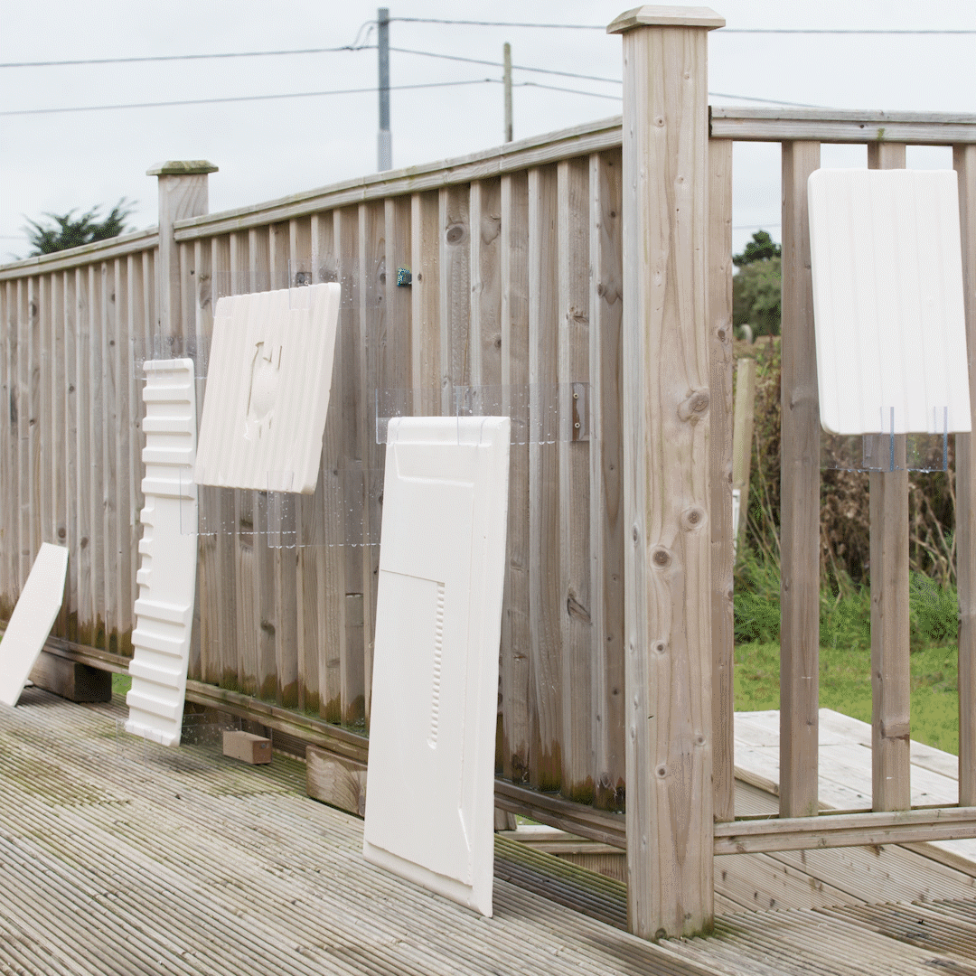 white rectangular slabs leaning against the porch of a one-story building by the sea.