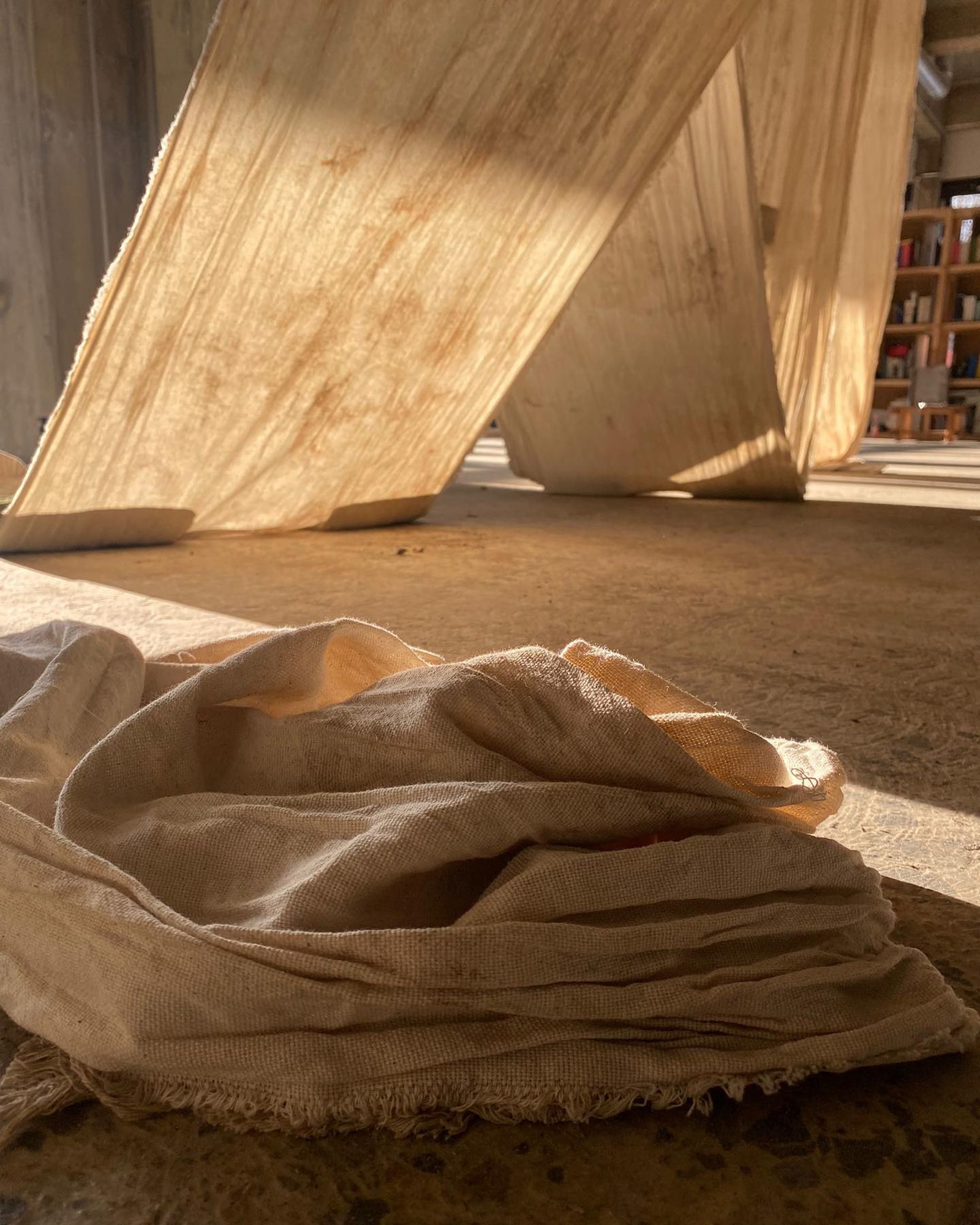 Large piece of fabric crumpled on the floor with other large pieces of fabric stretched in the background.