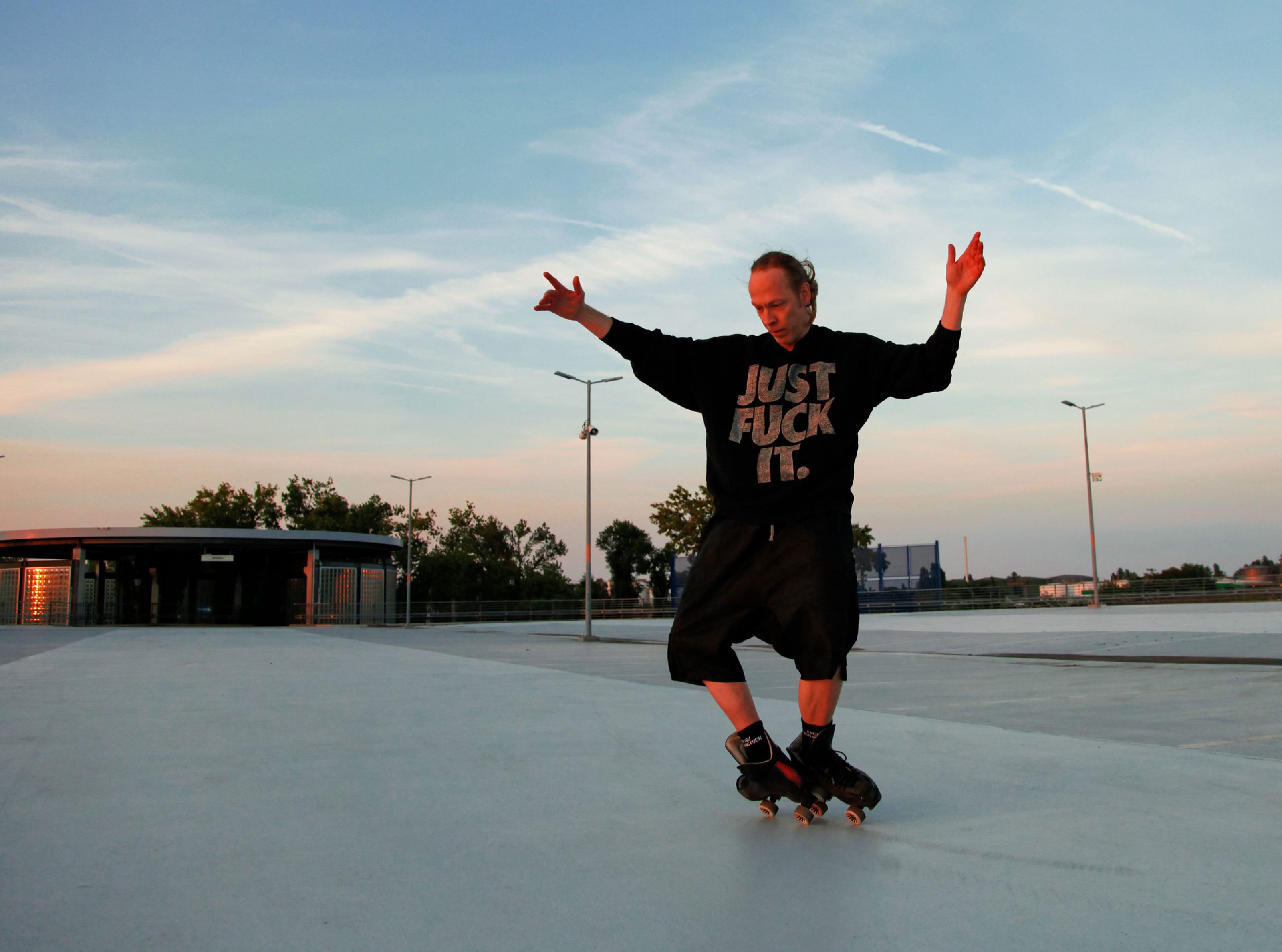 Sascha Dornhöfer is skating outdoors on a flat surface in a sweatshirt with the words "just fuck it" on it.