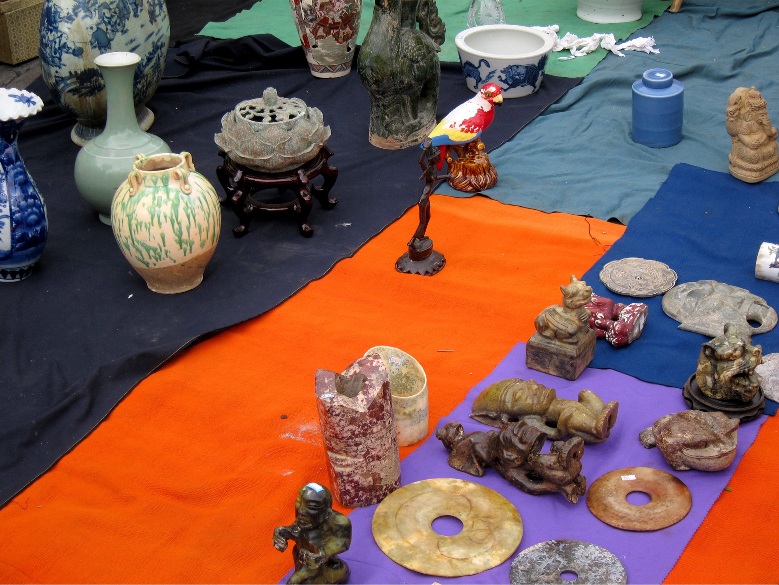 Small antique objects are placed on rectangular fabrics in purple, blue, lavert and green.