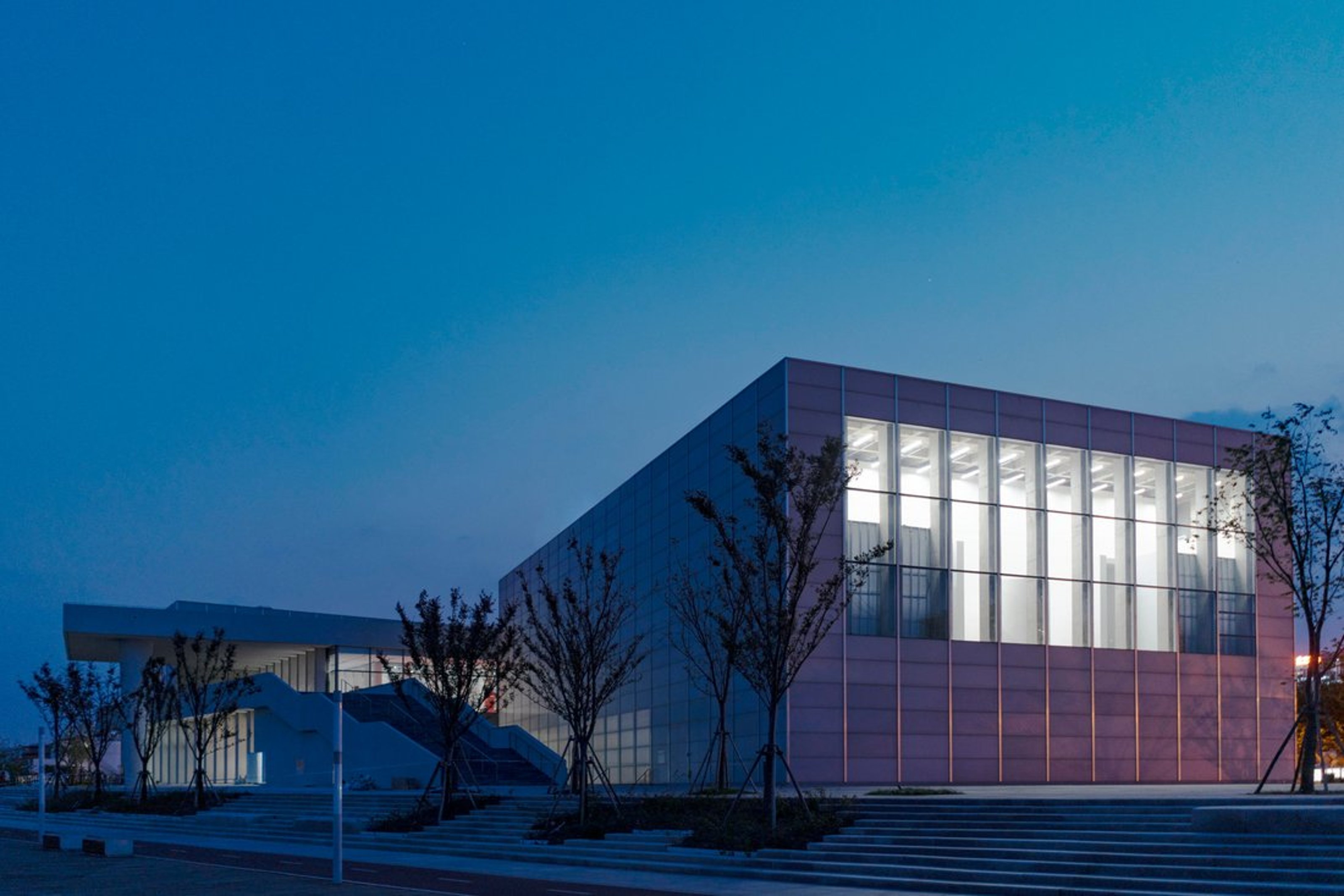 Close-up view from the outside of the West Bund Museum in Shanghai at night.