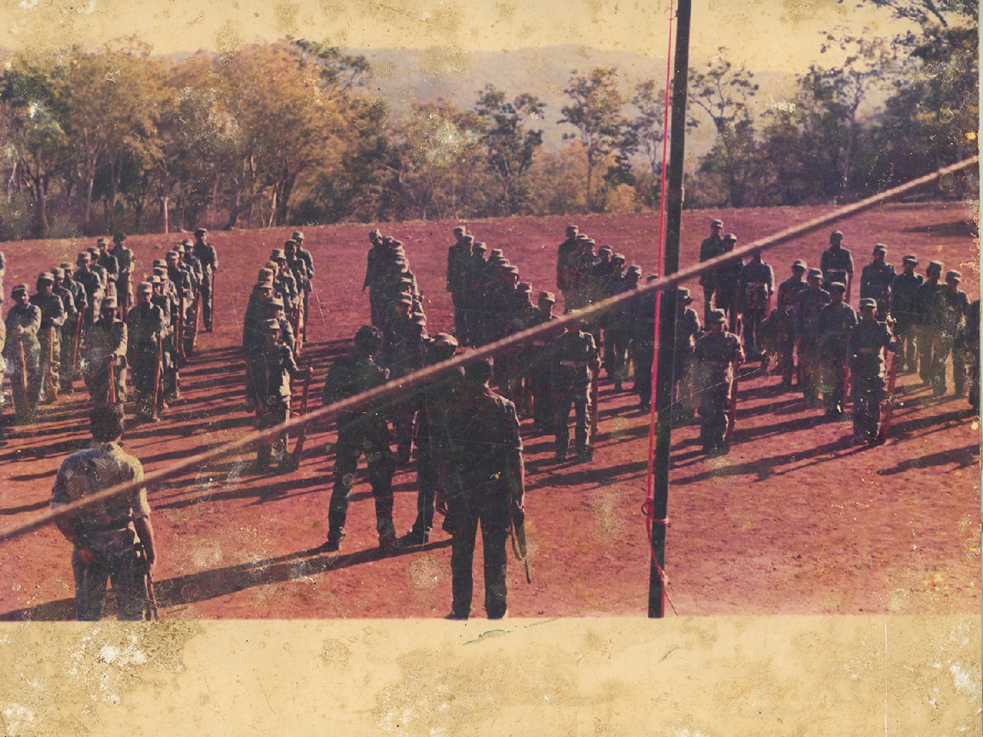 A top view of a group of uniformed soldiers on a flat, dirt-floor field.