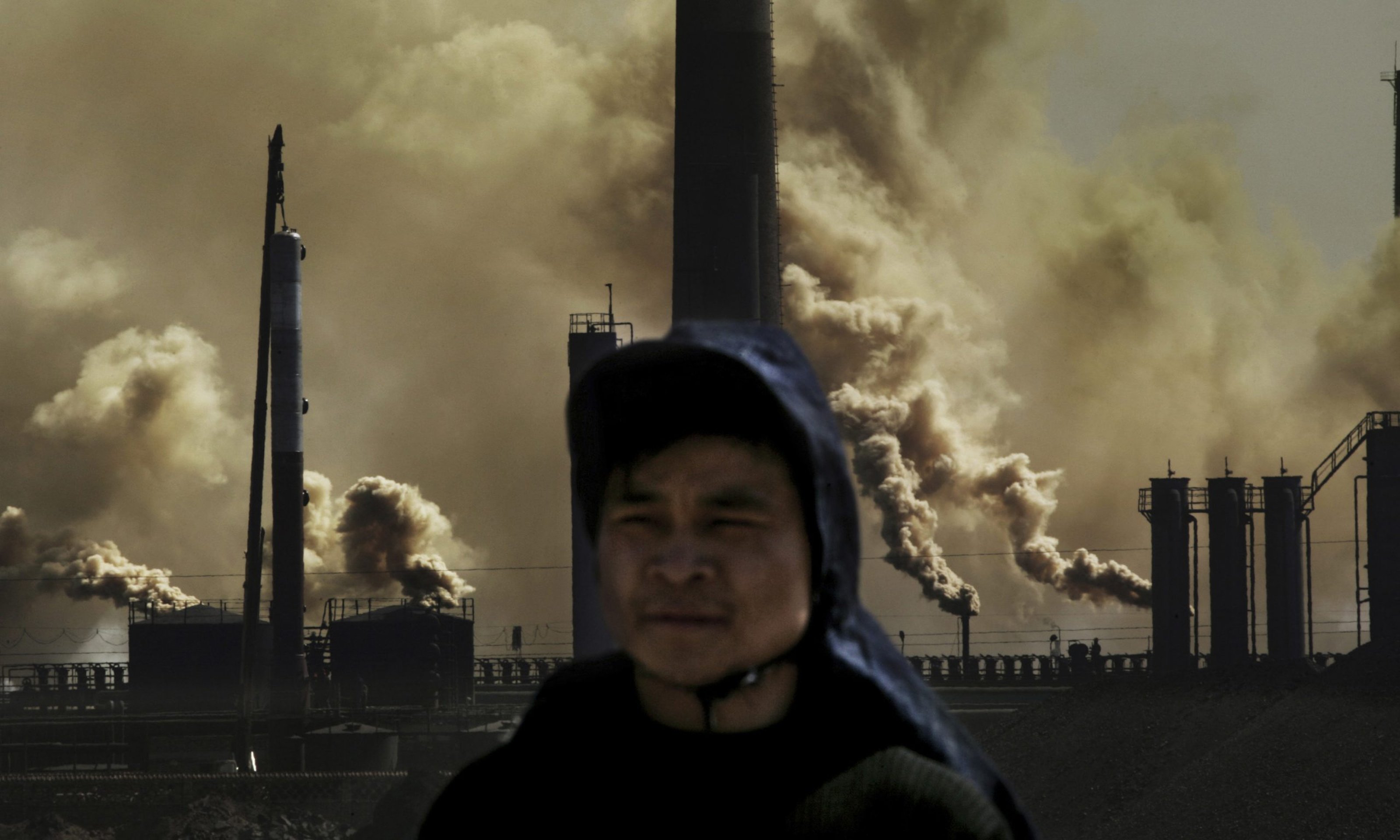 worker standing in front of factory releasing heavy fumes