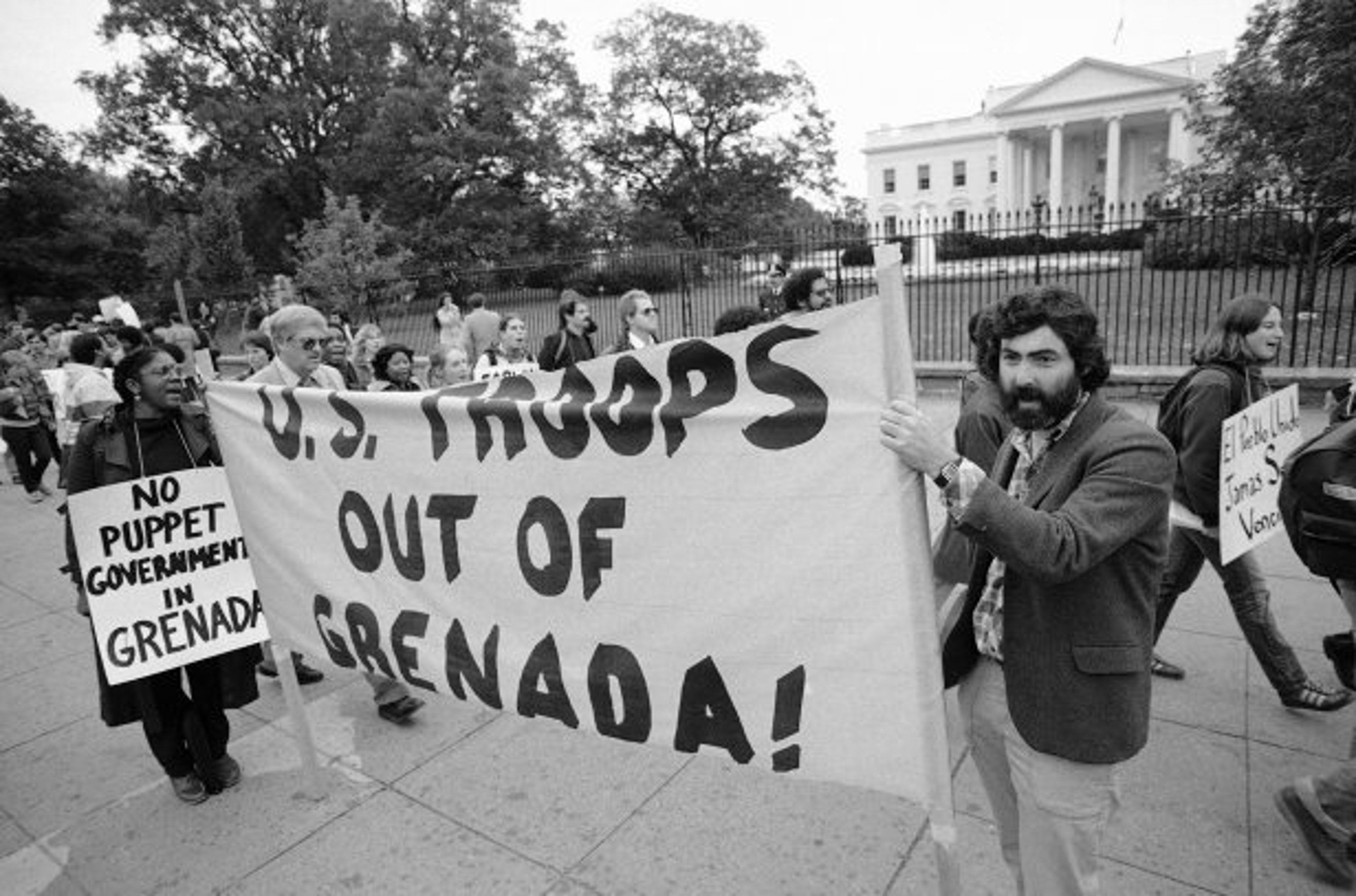 Protestors holding up a sign that reads: US troops out of Grenada!
