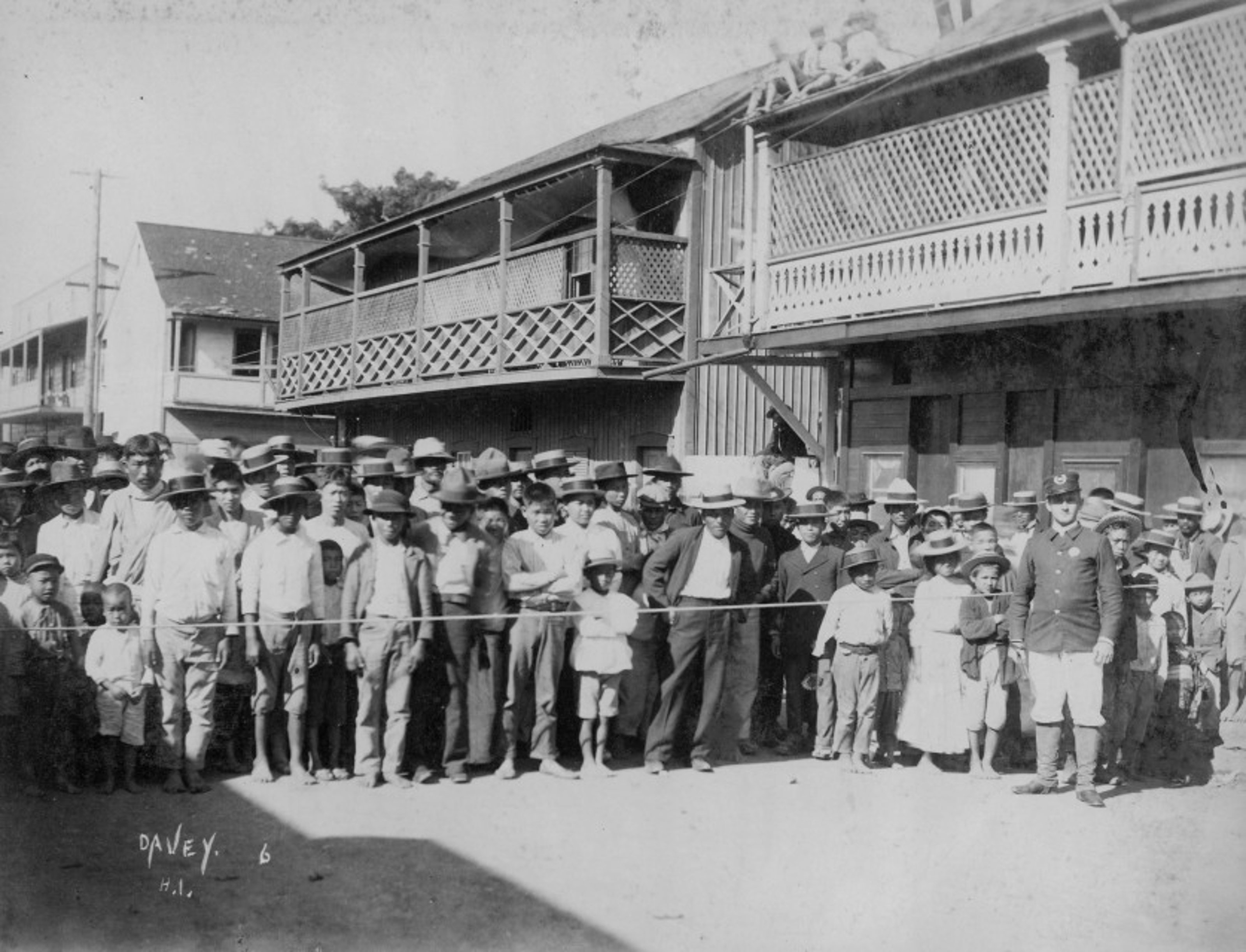 Asian community of Honolulu's Chinatown behind a rope, with an officer standing in front on the other side of the rope