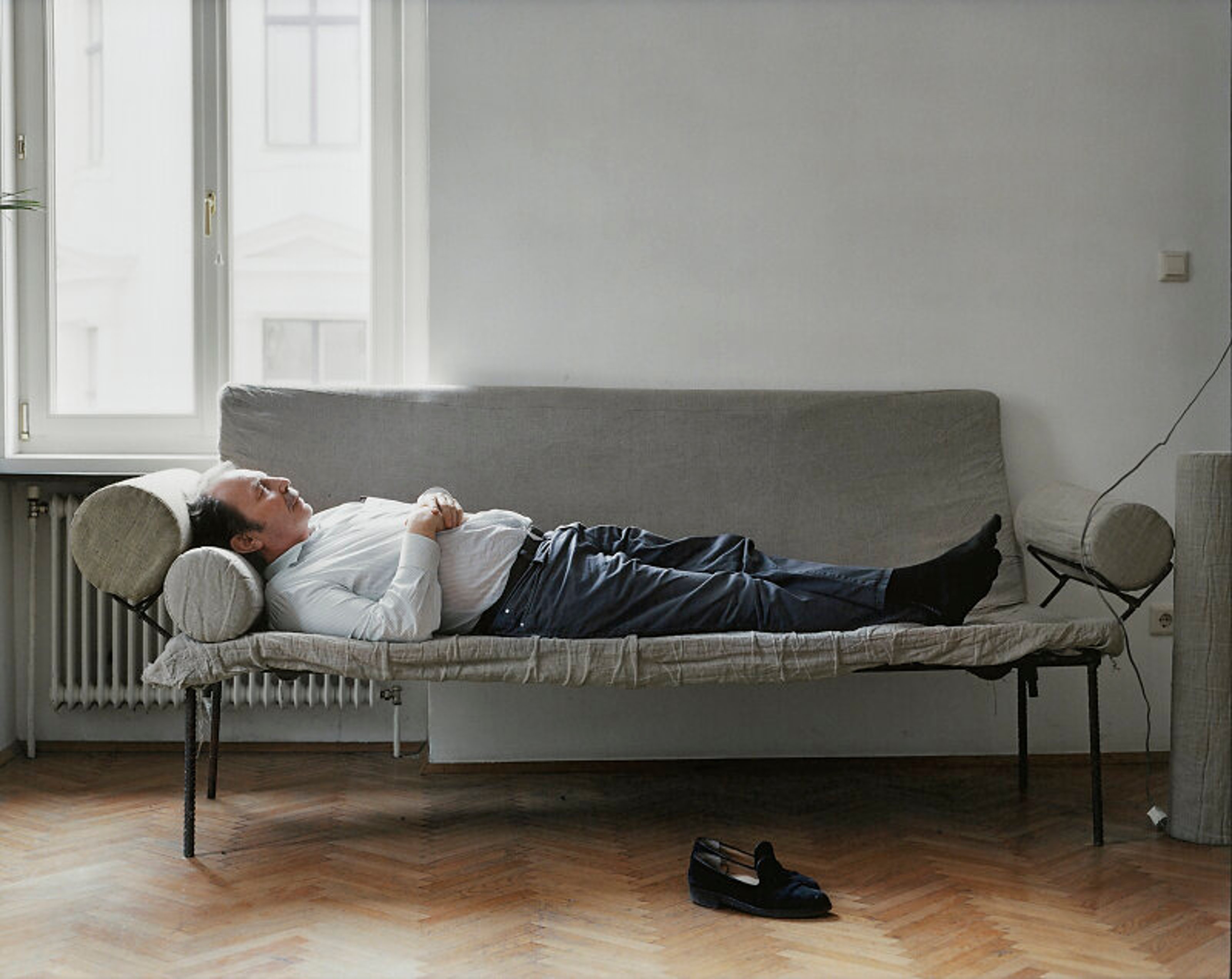 Franz West reclining on a couch indoors