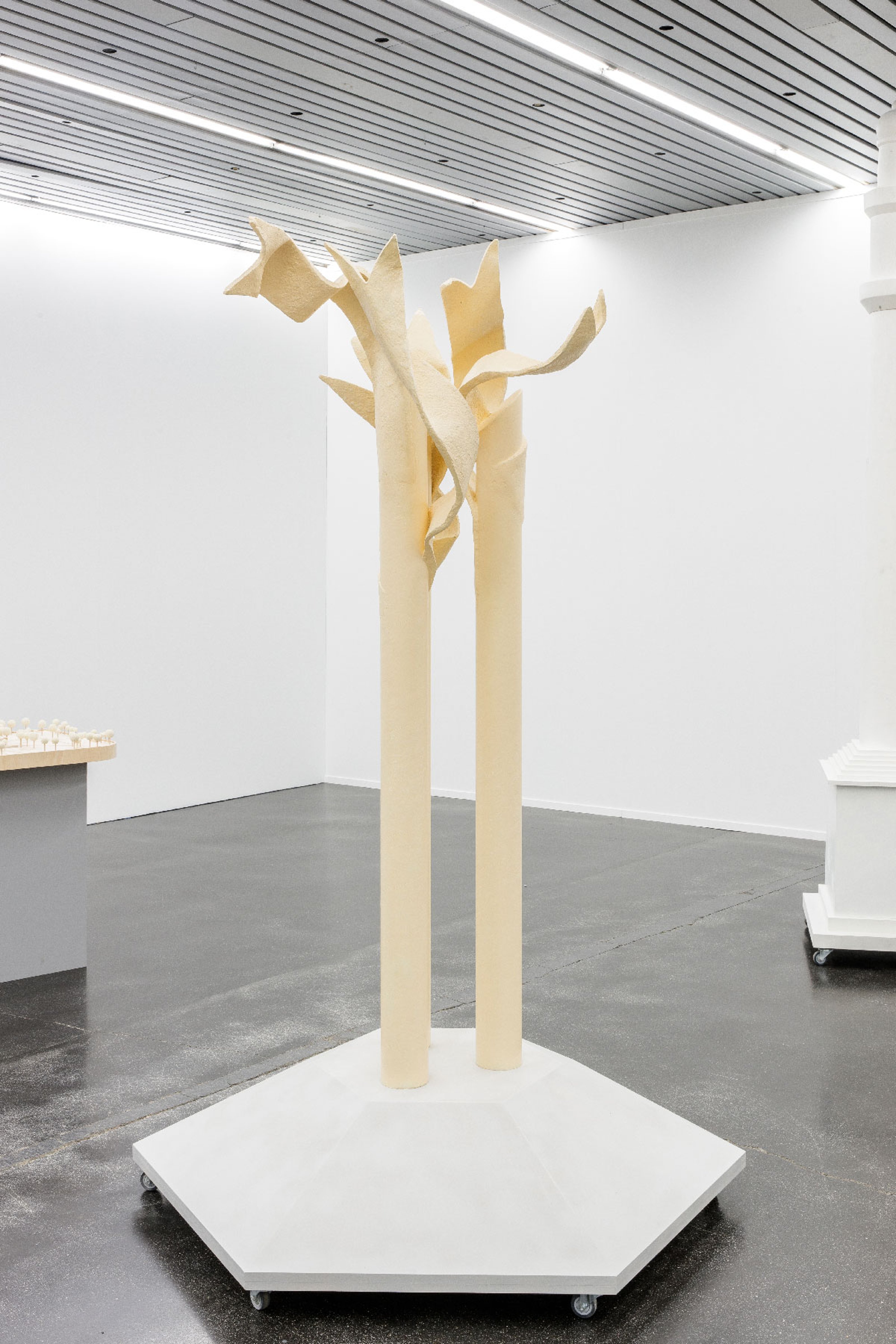 A large size model of a monument, two parallel pipe shaped figures that seem to hug at the top, as if simplified tree branches are hugging one another