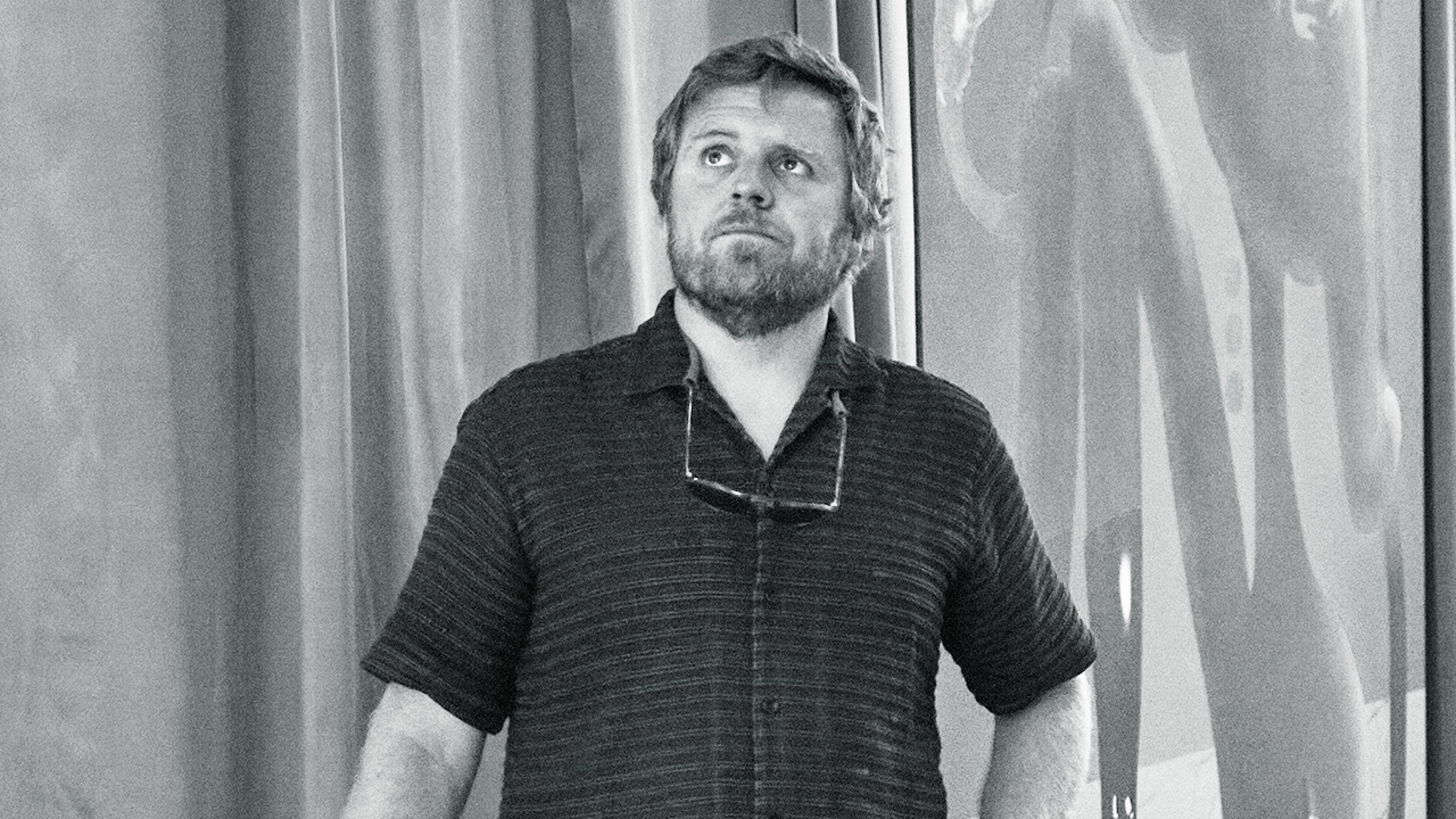 Black and white image of Carl Kostyal, the owner of Carl Kostyal Gallery in London, standing up and looking up