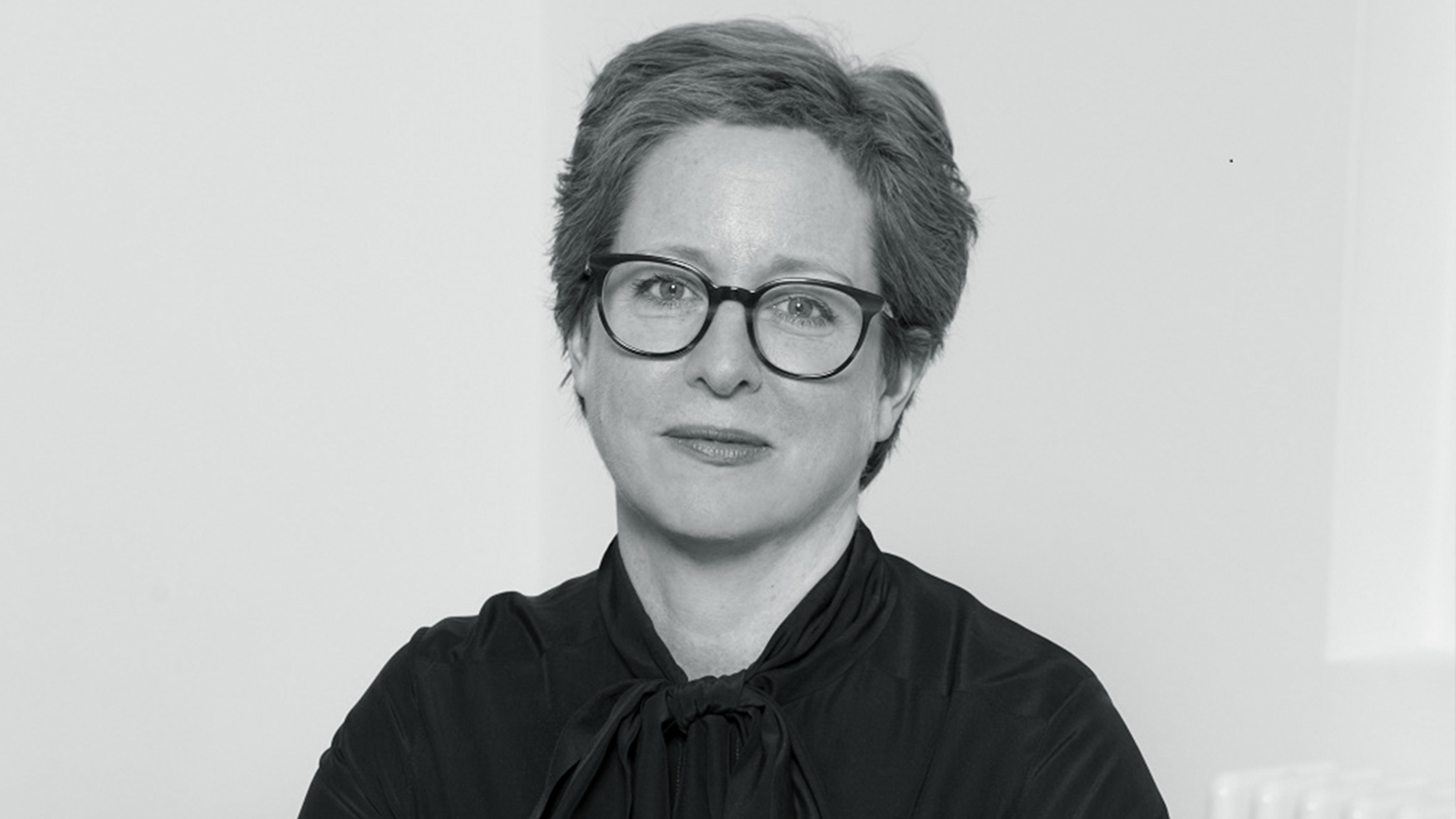 Black and white image of Esther Schipper on a blank background, smiling into the camera