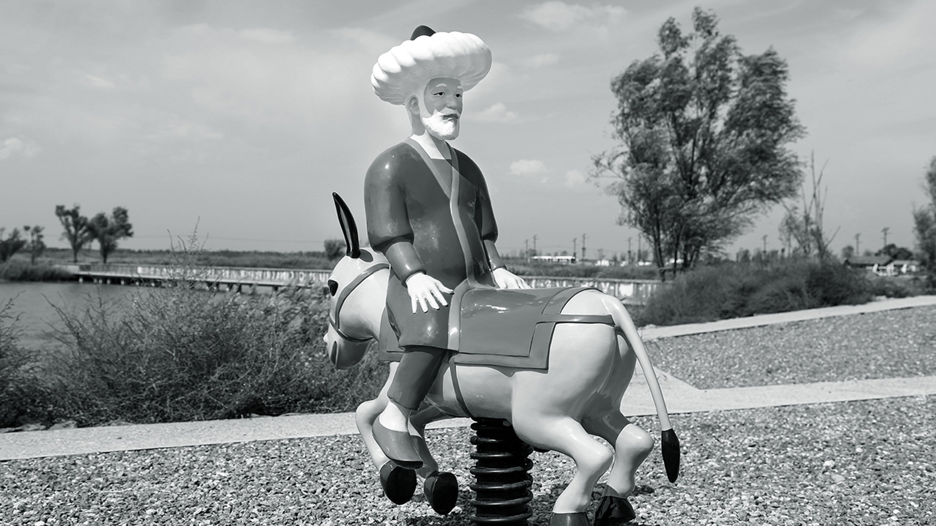 Black and white image of a sculpture of Molla Nasreddin sitting on a donkey backwards