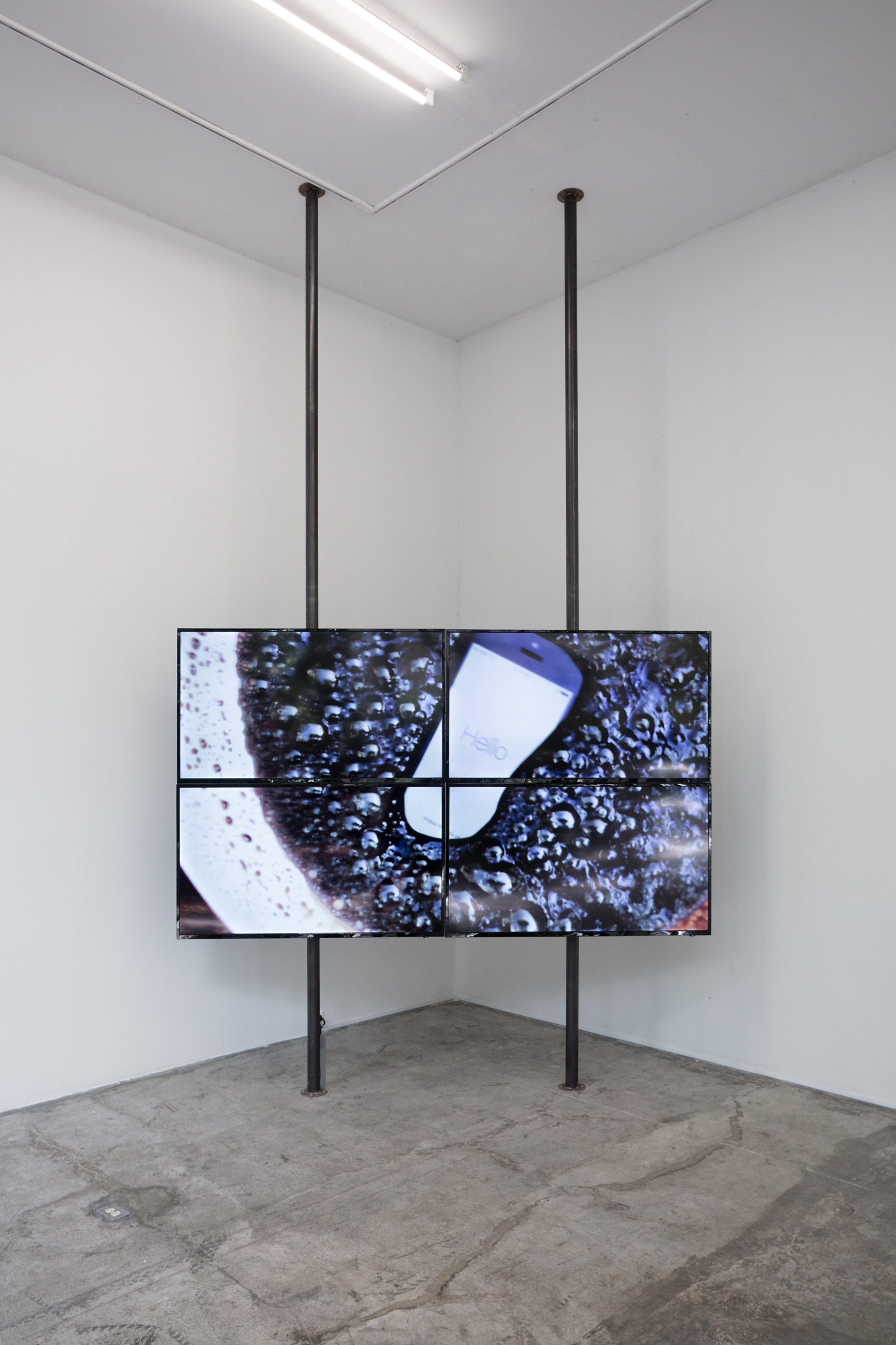 Video installation from a distance; on the screen an iPhone is being boiled in Coca-Cola, the iPhone screen shows the