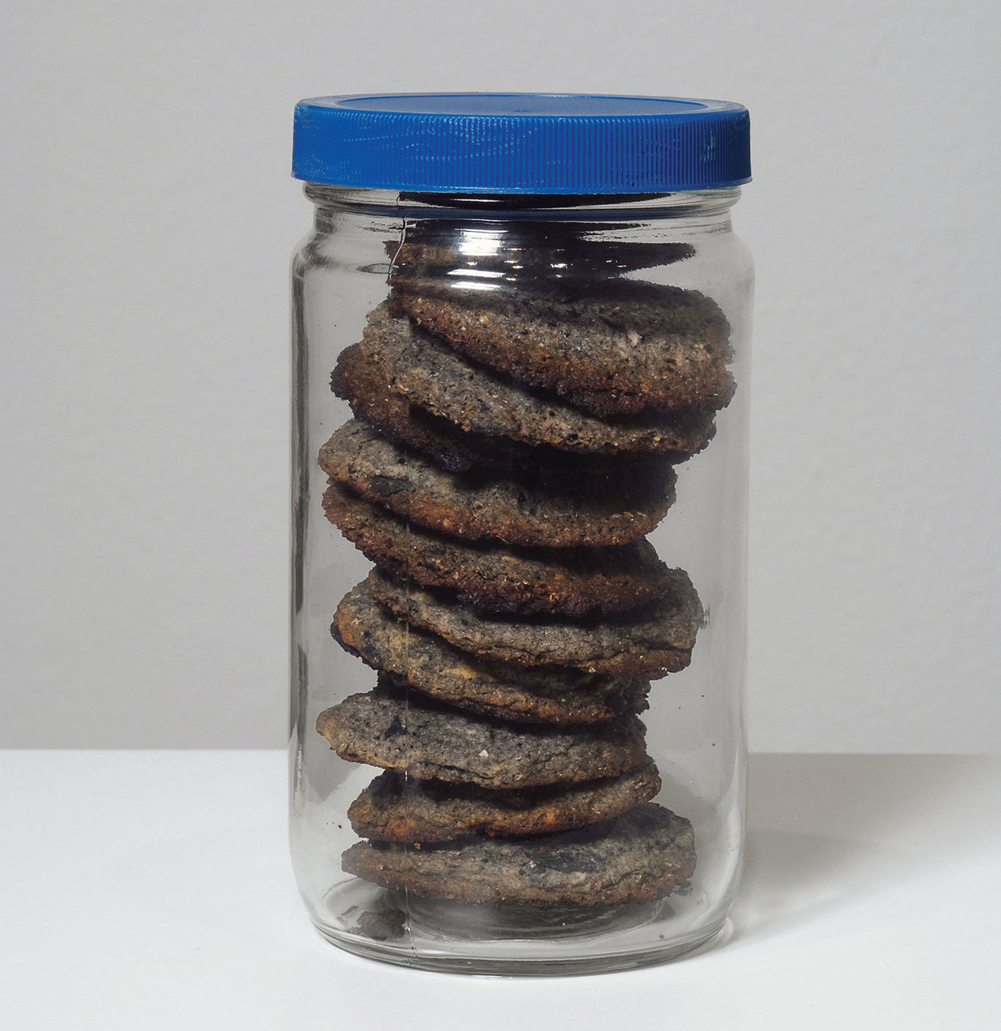 A glass jar holding ash cookies made with burned paintings.