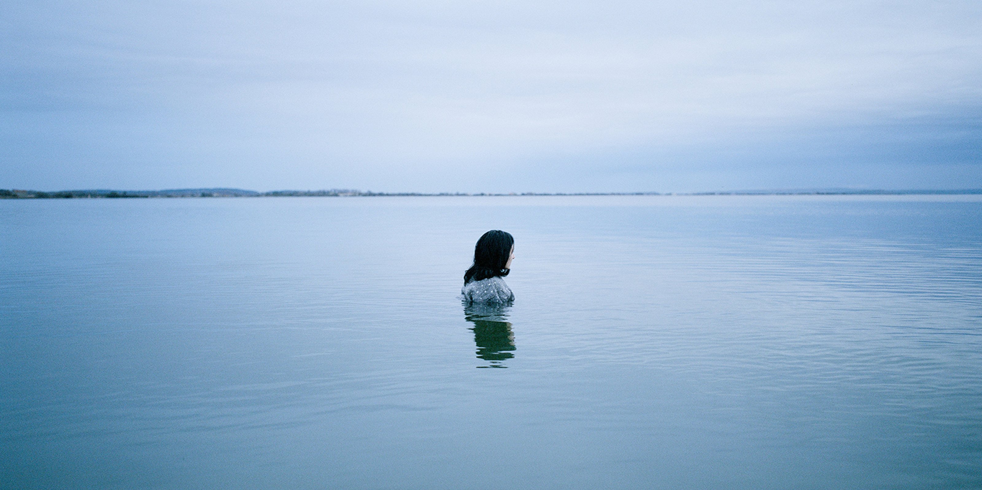 Wide shot of woman standing in a large body of water