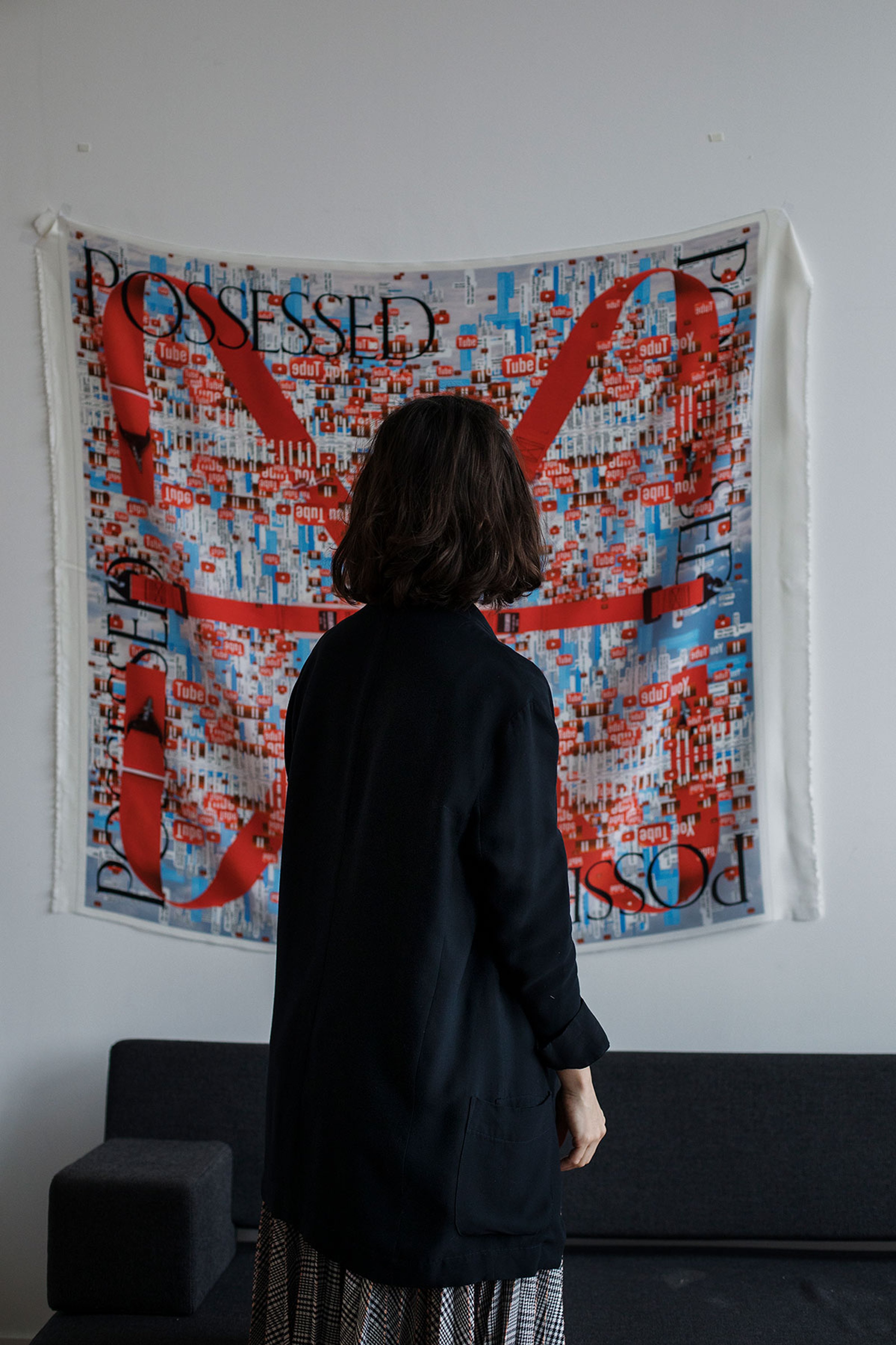 A woman looking at a tapestry on the wall which is an artwork by metahaven