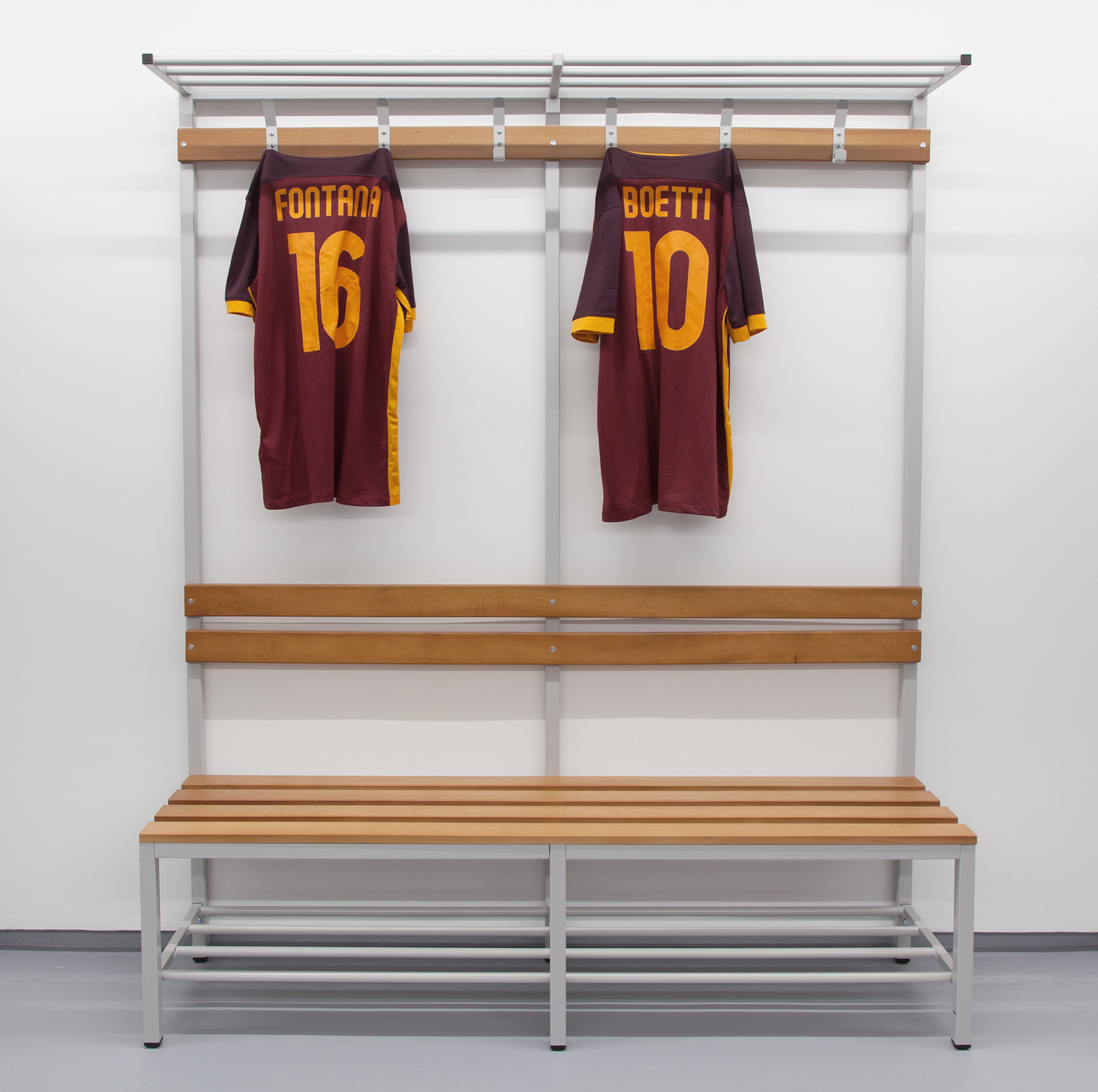 Two sport uniforms hanging on a rack in a dressing room