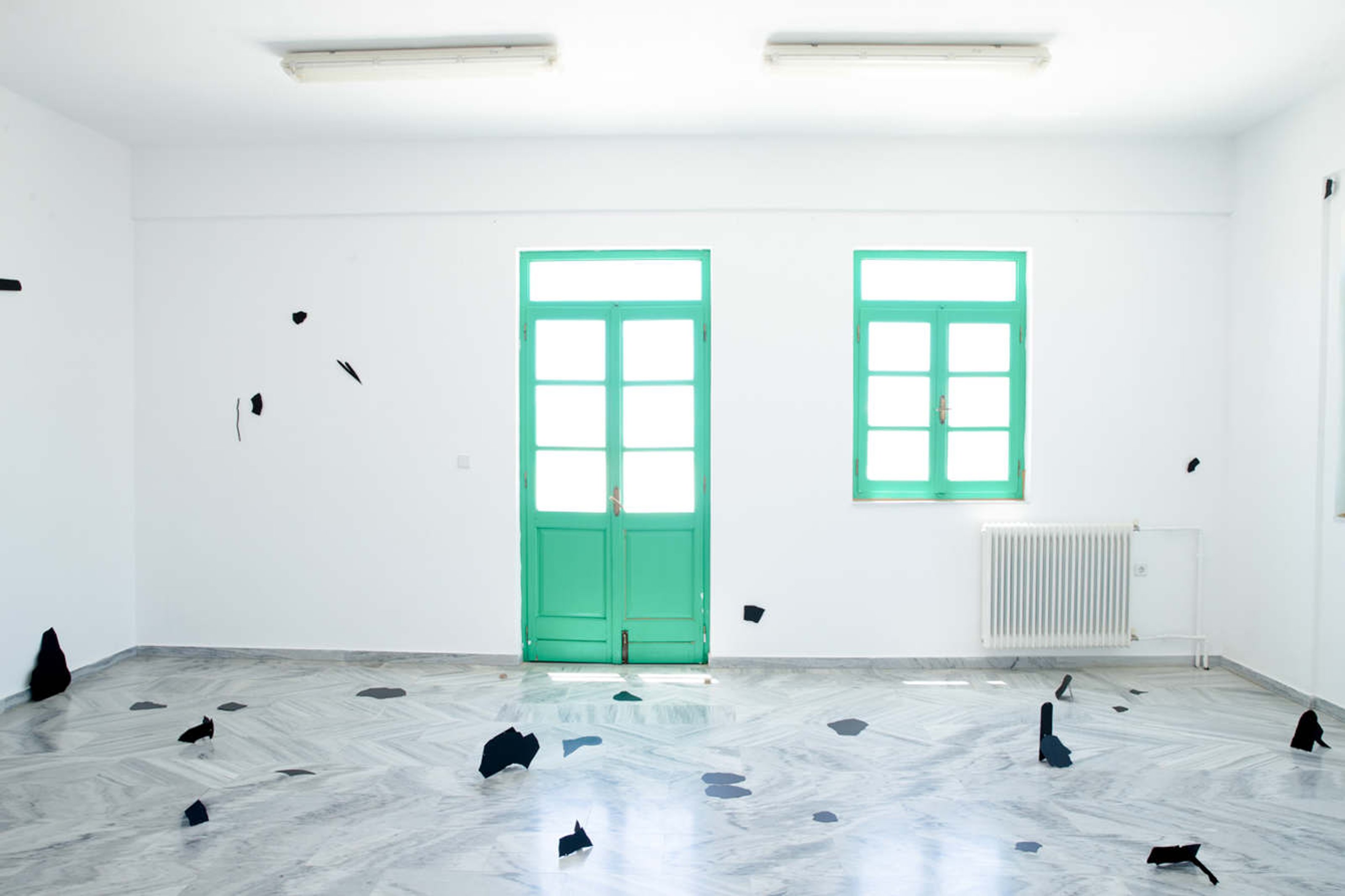 Black, abstractly shaped textile pieces on a white room.