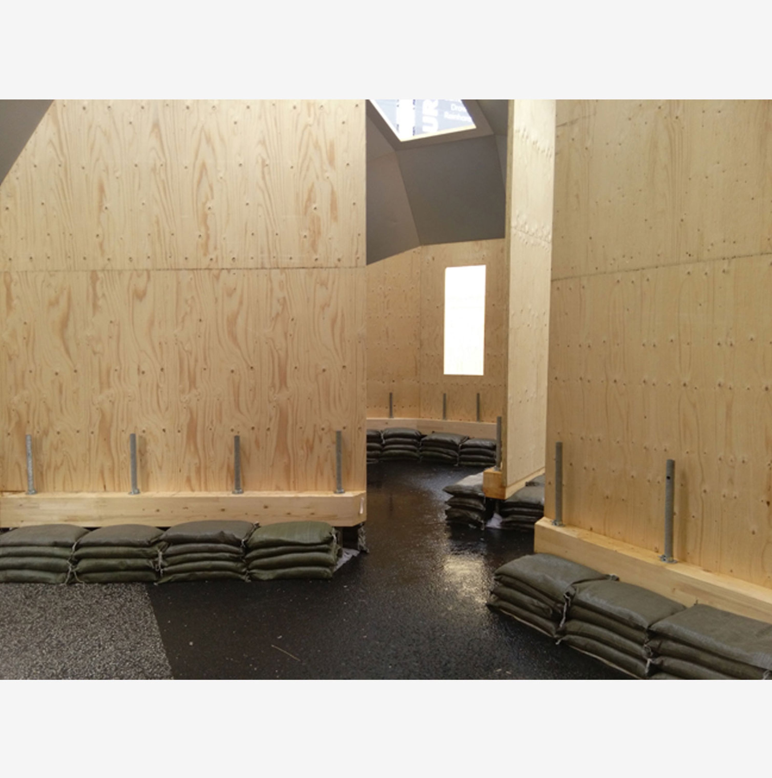 Interior view of a space with wooden walls and black sand bags on the floor