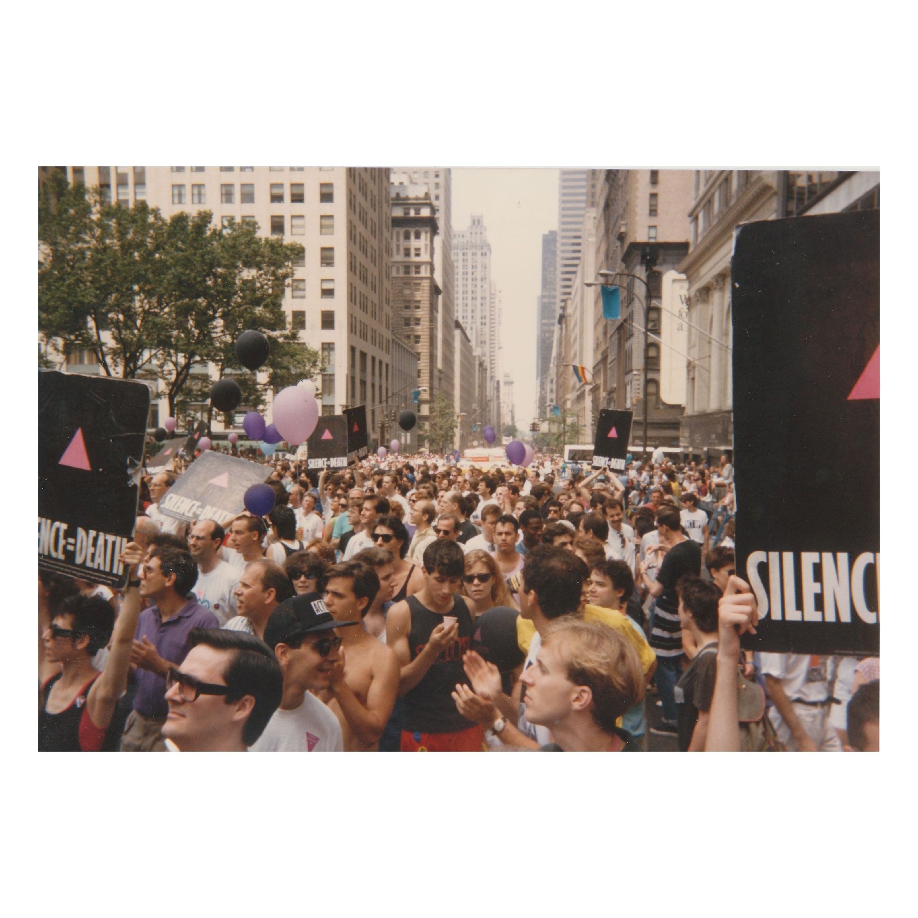 Photograph of LGBTQ protesters marching on an avenue holding signs