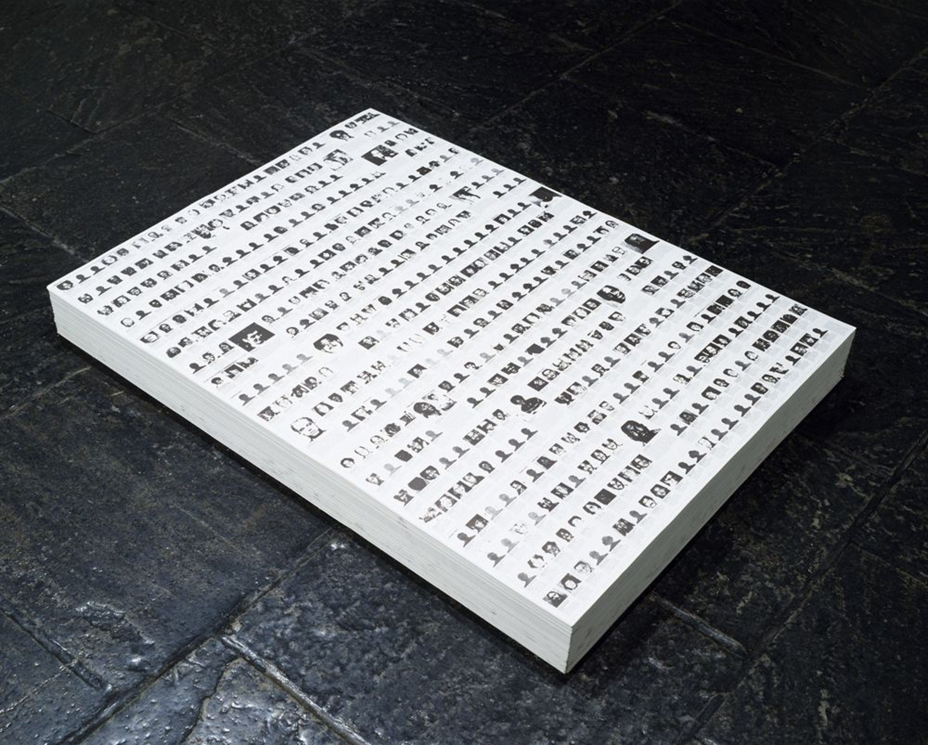 A nine-inch-high stack of papers featuring the images and descriptions of 460 people killed by gunshot in the United States from May 1-7, 1989.