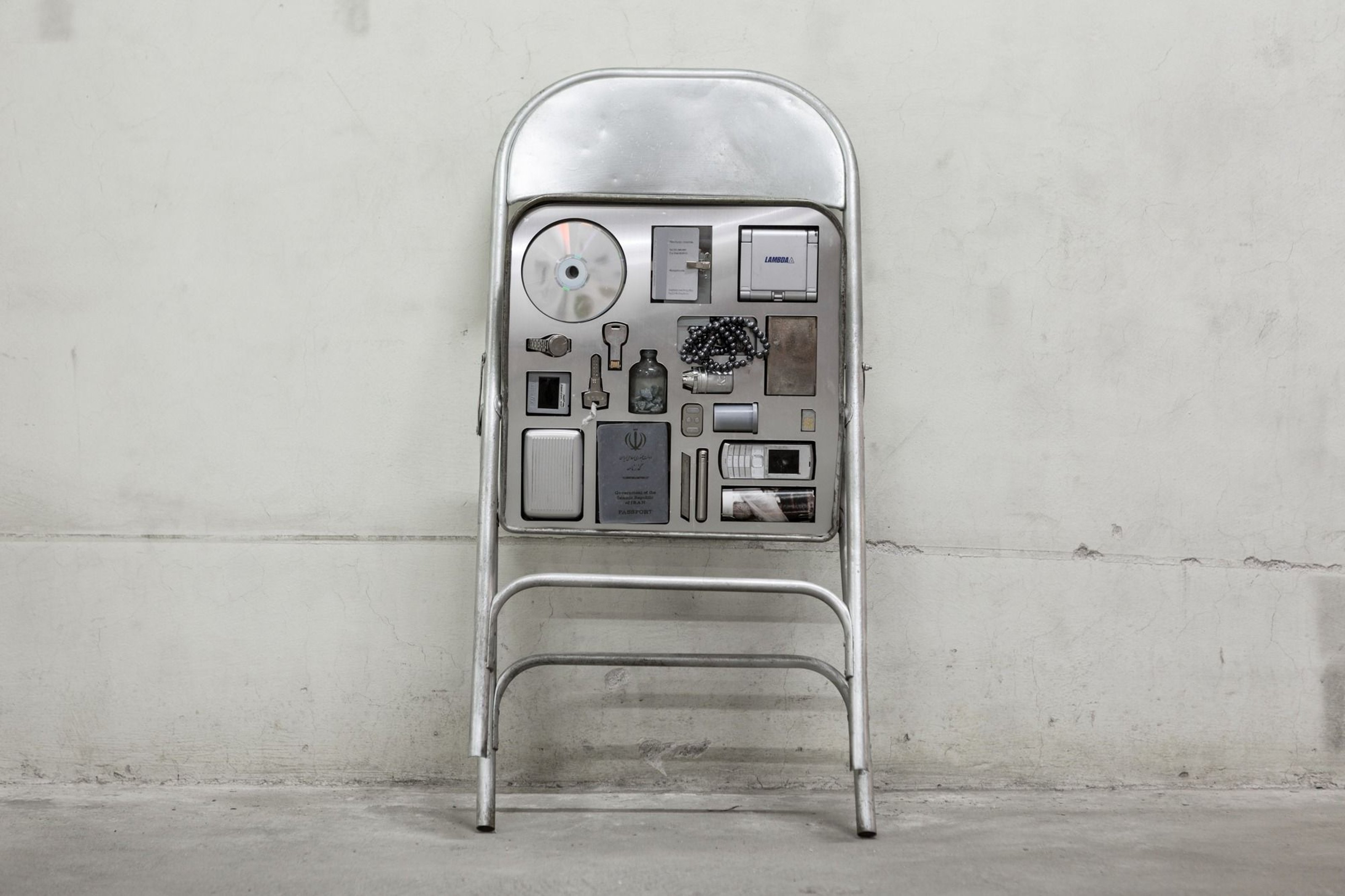 Image of folded silver metal chair with contraband placed underneath the seat