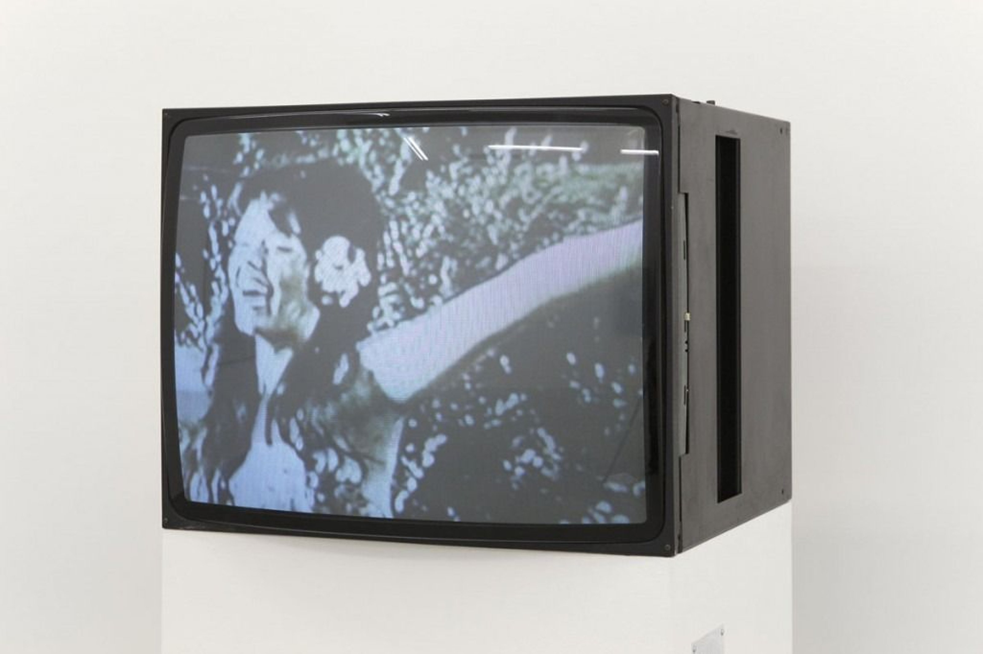 An old TV on a pedestal, playing a Super 8 film on loop