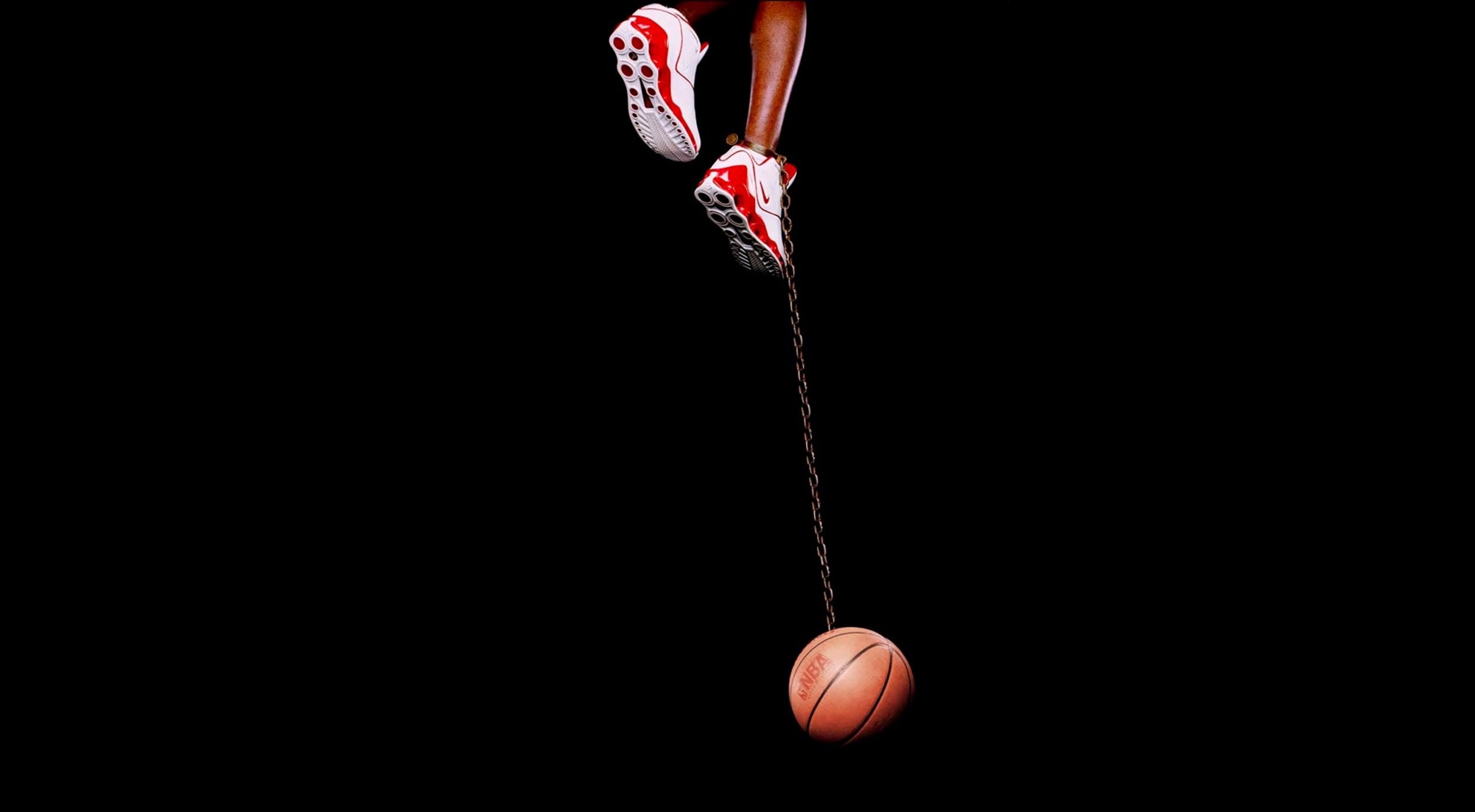With a metal chain, a basketball hanging off a pair of feet in Jordan sneakers, Artwork by Hank Willis Thomas