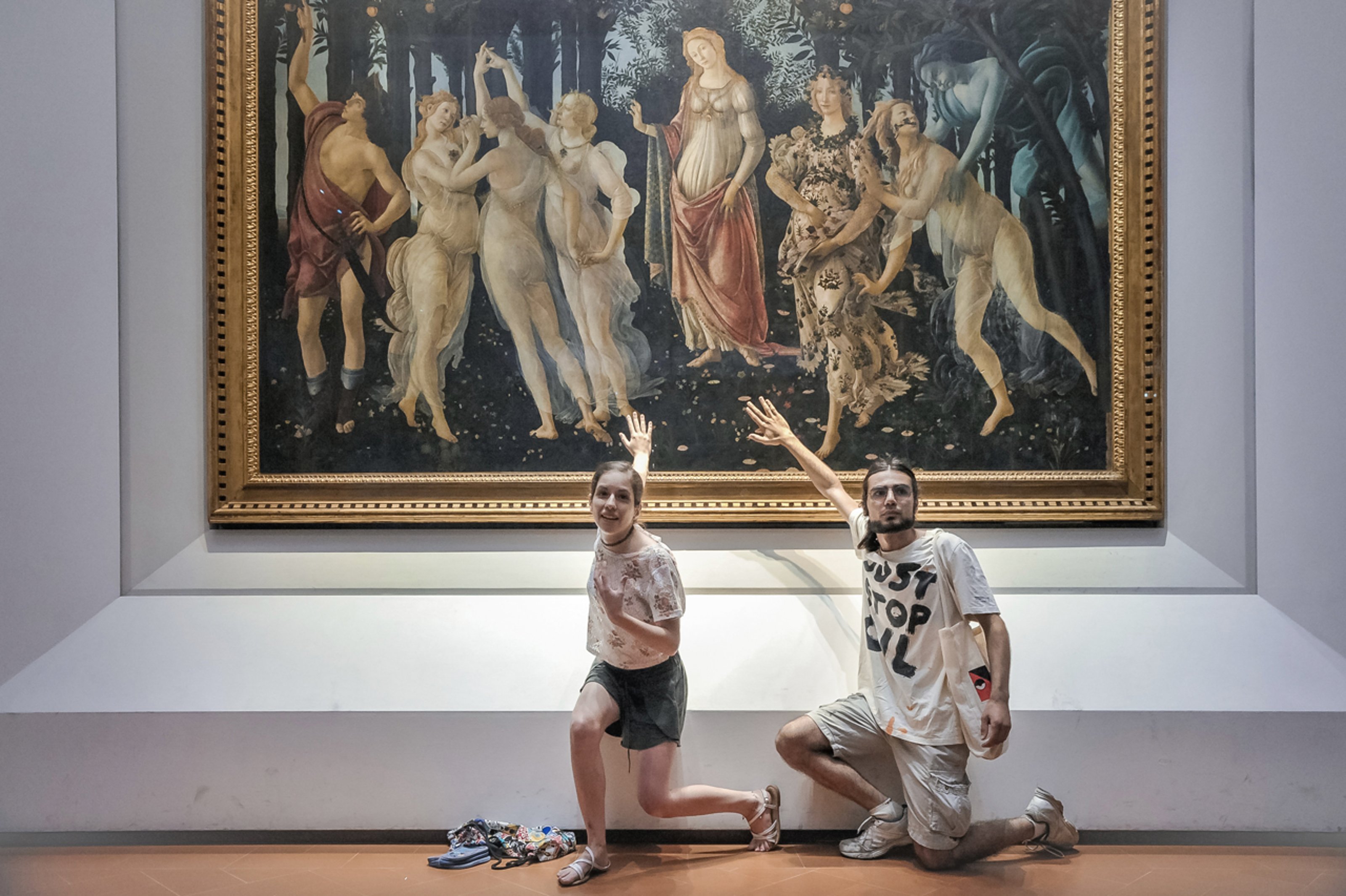 An image showing two climate protestors with their hands glued to Sandro Boticelli’s _Primavera_ at _Galleria Degli in Florence on July 2022.